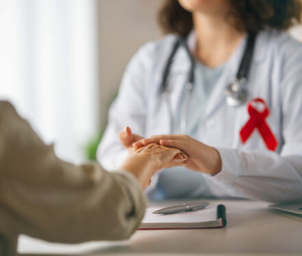 Colour ribbon for concept of illness awareness. Female patient listening to doctor in medical office. Raising knowledge on people living with disease.